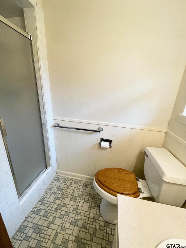 114 Briar Ln, Crockett, TX 75835 - bathroom featuring toilet, a stall shower, and a wainscoted wall