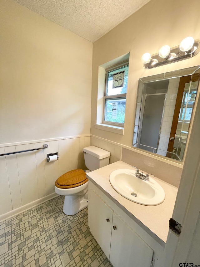 114 Briar Ln, Crockett, TX 75835 - full bathroom with a stall shower, toilet, a wainscoted wall, vanity, and a textured ceiling