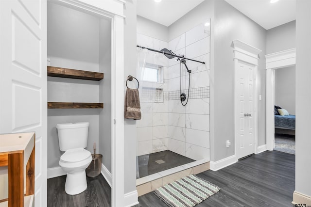 bathroom featuring a tile shower, hardwood / wood-style floors, and toilet