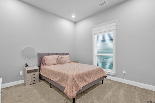 bedroom with light colored carpet and multiple windows