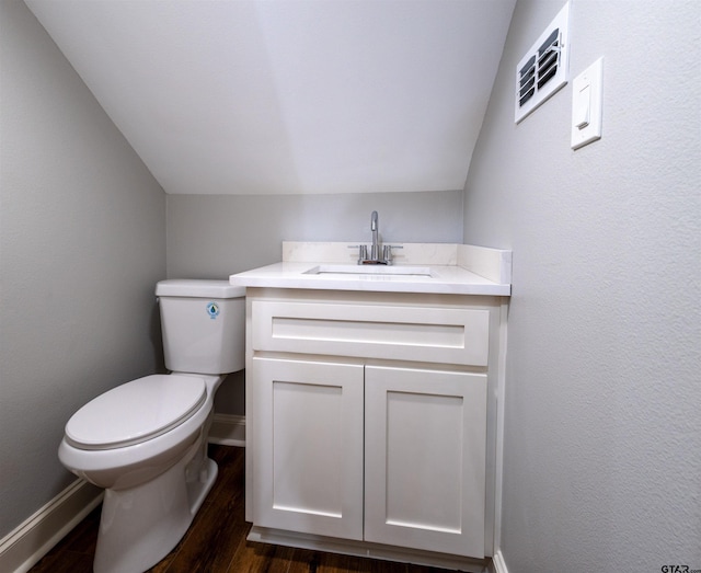 bathroom with hardwood / wood-style flooring, lofted ceiling, vanity, and toilet