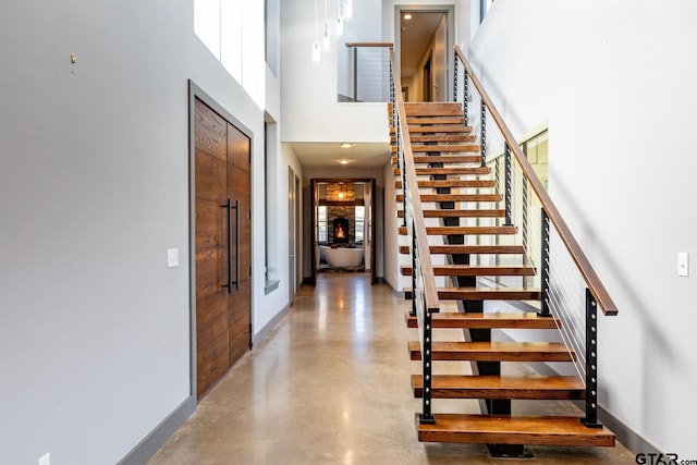 stairs with a high ceiling, concrete floors, baseboards, and a wealth of natural light