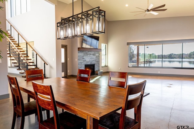 dining room featuring a towering ceiling, stairs, baseboards, and a ceiling fan