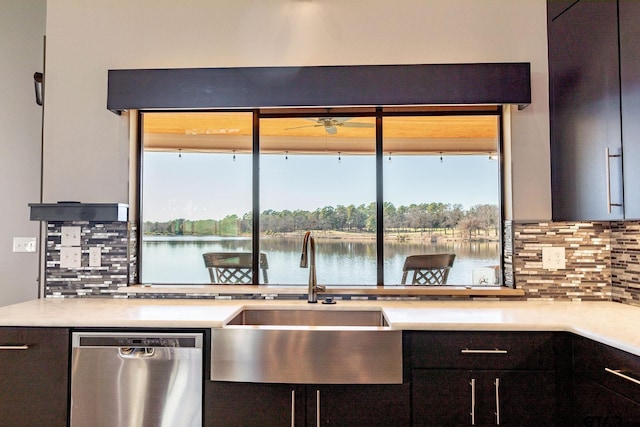 kitchen with a water view, a sink, light countertops, decorative backsplash, and dishwasher