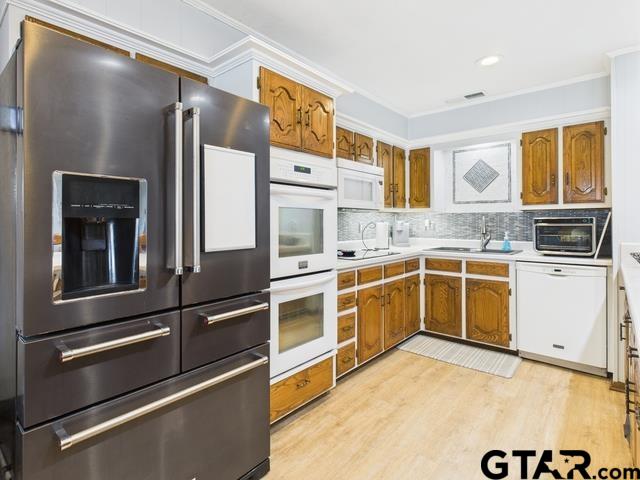 14227 Melody Ln, Malakoff, TX 75148 - kitchen featuring white appliances, brown cabinets, a sink, light wood-type flooring, and light countertops