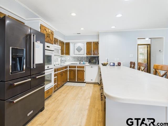 14227 Melody Ln, Malakoff, TX 75148 - kitchen featuring white appliances, a peninsula, a sink, brown cabinetry, and ornamental molding