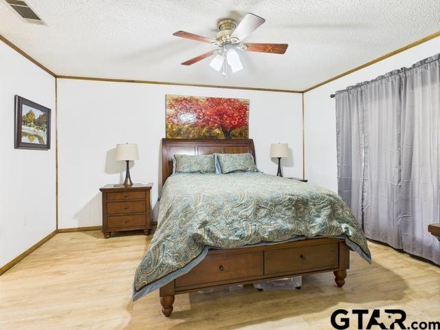 14227 Melody Ln, Malakoff, TX 75148 - bedroom with a textured ceiling, wood finished floors, ornamental molding, and ceiling fan