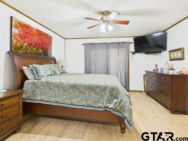 14227 Melody Ln, Malakoff, TX 75148 - bedroom with light wood-type flooring, a textured ceiling, and a ceiling fan