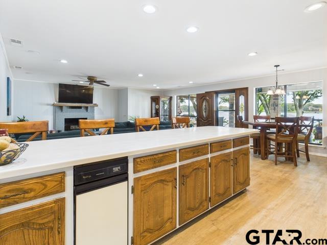 14227 Melody Ln, Malakoff, TX 75148 - kitchen with a brick fireplace, a ceiling fan, light wood-type flooring, recessed lighting, and light countertops