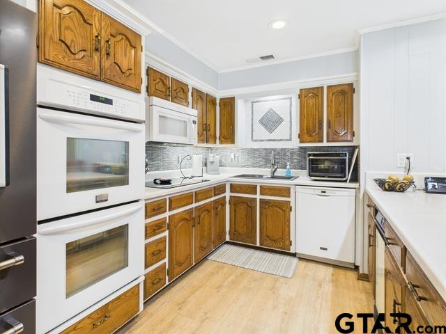 14227 Melody Ln, Malakoff, TX 75148 - kitchen featuring white appliances, a sink, brown cabinetry, light countertops, and ornamental molding