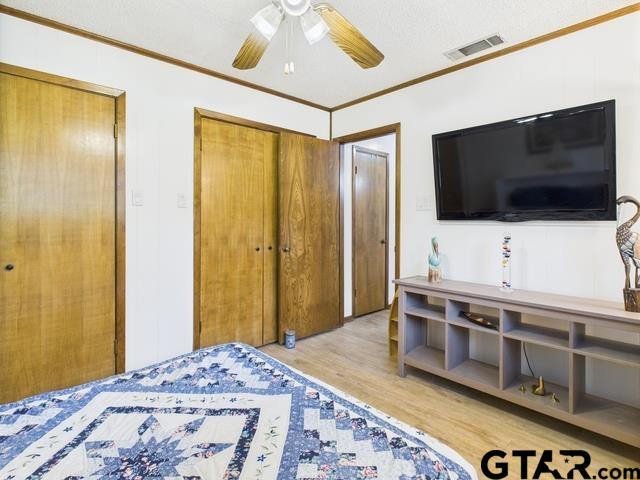 14227 Melody Ln, Malakoff, TX 75148 - bedroom featuring light wood-style floors, ornamental molding, a ceiling fan, and a closet