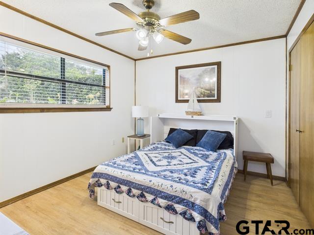 14227 Melody Ln, Malakoff, TX 75148 - bedroom with ornamental molding, light wood-style floors, baseboards, a ceiling fan, and a closet