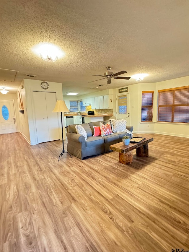 living room featuring a textured ceiling, light hardwood / wood-style flooring, and ceiling fan