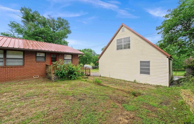 109 Maxine St, Mineola, TX 75773 - view of property exterior with metal roof, brick siding, a lawn, and a deck