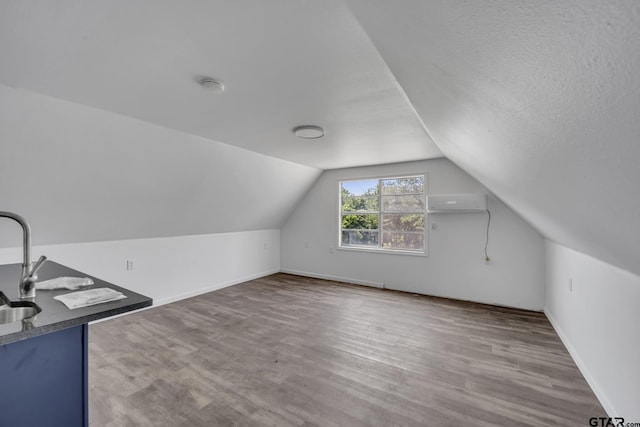 109 Maxine St, Mineola, TX 75773 - additional living space with lofted ceiling, wood finished floors, a wall unit AC, baseboards, and a sink