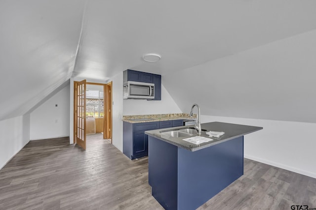 109 Maxine St, Mineola, TX 75773 - kitchen with stainless steel microwave, blue cabinets, a sink, wood finished floors, and vaulted ceiling