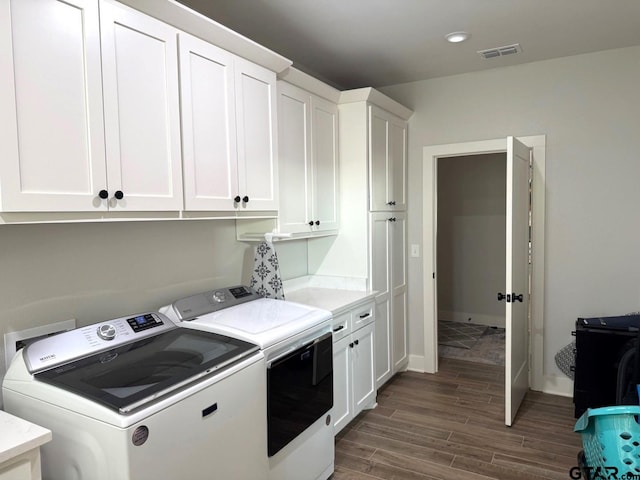 laundry area with cabinets, dark hardwood / wood-style flooring, and washer and clothes dryer