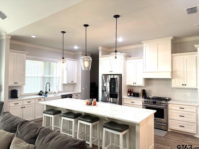 kitchen with a kitchen bar, sink, white cabinetry, a center island, and stainless steel appliances