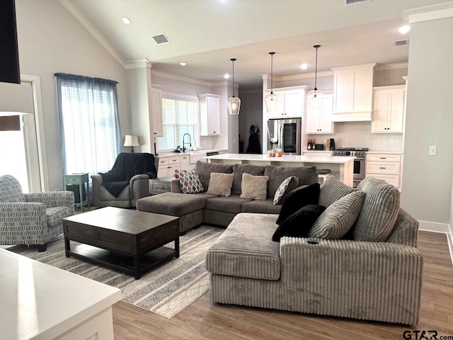 living room featuring vaulted ceiling, crown molding, and light hardwood / wood-style flooring