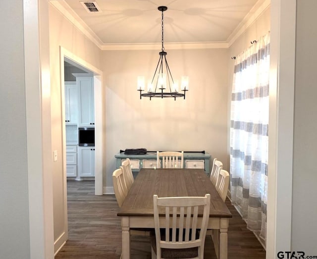 dining area with crown molding, an inviting chandelier, and dark wood-type flooring