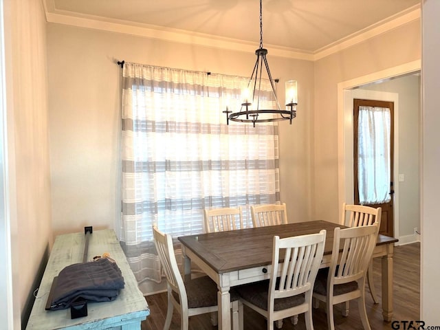 dining space with a notable chandelier, dark wood-type flooring, ornamental molding, and a healthy amount of sunlight