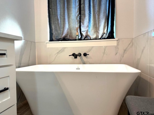 bathroom featuring a washtub, wood-type flooring, and tile walls