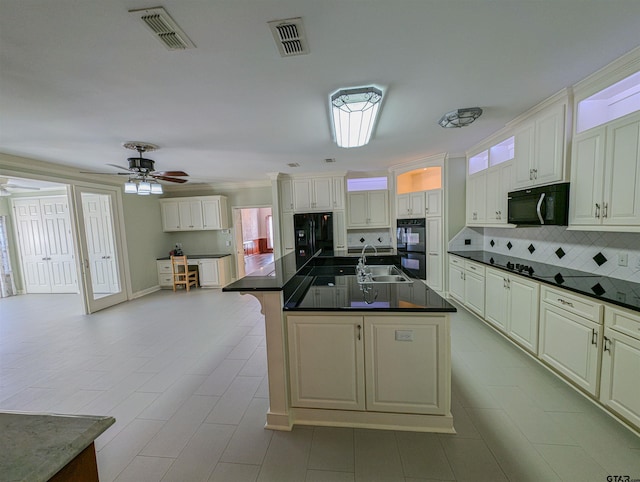 kitchen featuring sink, black appliances, tasteful backsplash, ceiling fan, and a kitchen island with sink