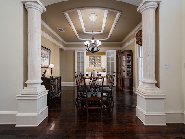 dining area with an inviting chandelier, decorative columns, dark hardwood / wood-style floors, crown molding, and a raised ceiling