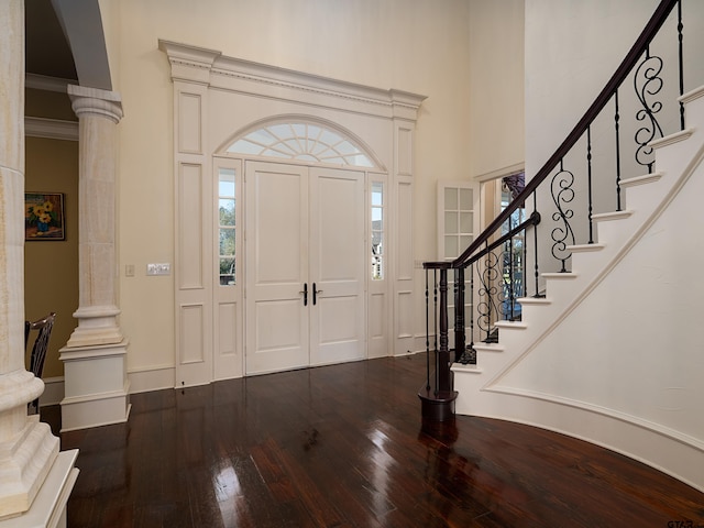 foyer featuring decorative columns, hardwood / wood-style flooring, and a towering ceiling