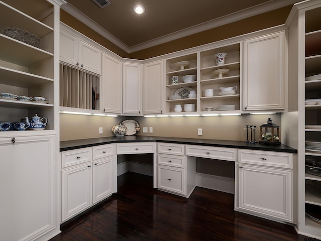 unfurnished office featuring built in desk, crown molding, and dark hardwood / wood-style flooring