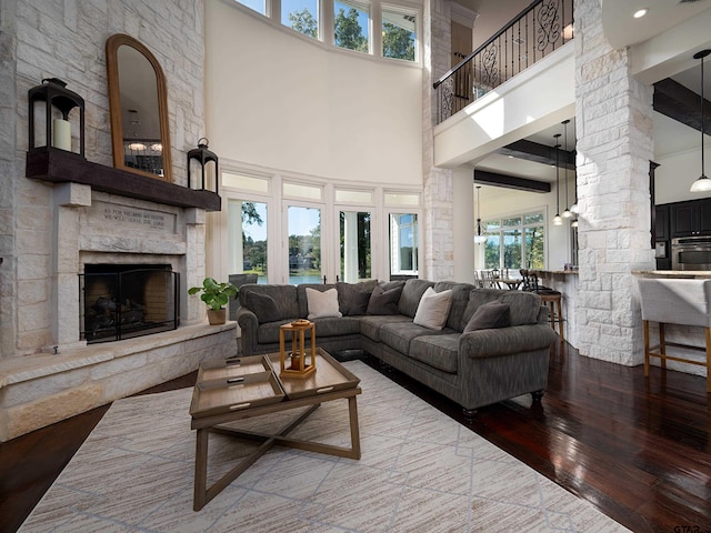 living room with a fireplace, wood-type flooring, beamed ceiling, and a high ceiling