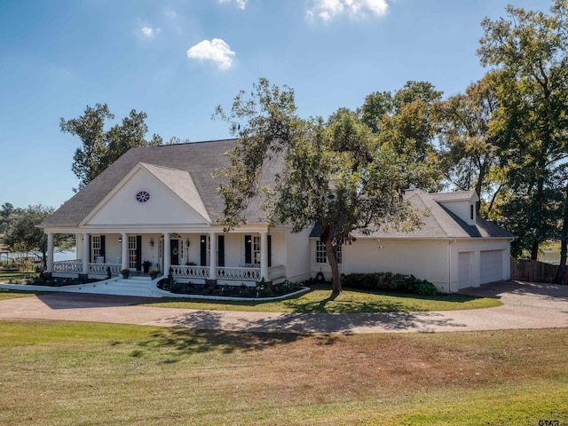 neoclassical / greek revival house with a garage, a porch, and a front lawn