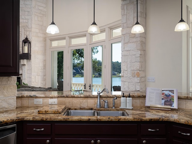 kitchen with decorative light fixtures, a water view, sink, and dark brown cabinetry