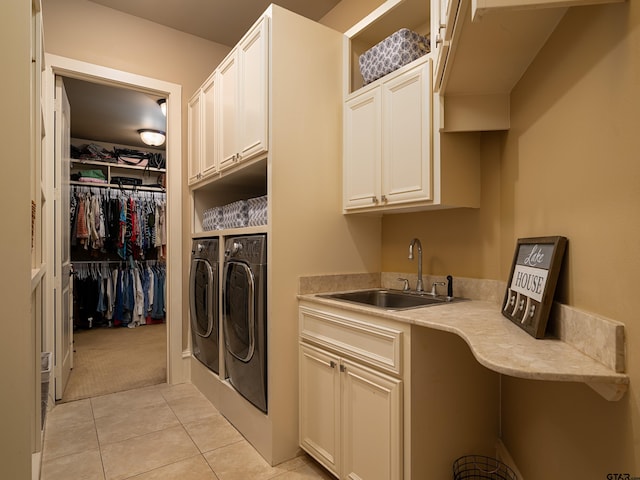 laundry area with washer and clothes dryer, cabinets, sink, and light tile patterned floors