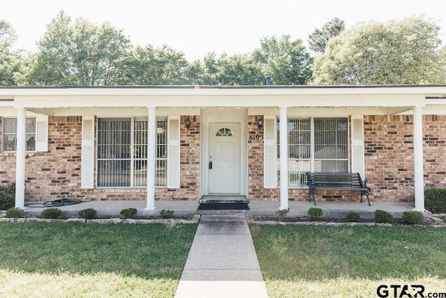 8105 Jewell Ln, Tyler, TX 75703 - entrance to property featuring brick siding, a yard, and a porch