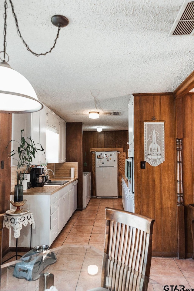 8105 Jewell Ln, Tyler, TX 75703 - kitchen featuring visible vents, oven, a sink, freestanding refrigerator, and wooden walls