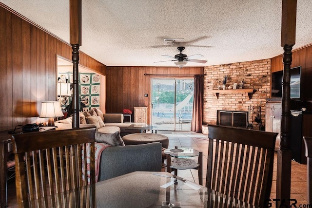8105 Jewell Ln, Tyler, TX 75703 - tiled living area with visible vents, a ceiling fan, a fireplace, wooden walls, and a textured ceiling