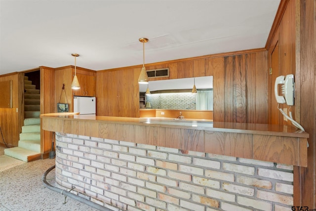 kitchen featuring brown cabinets, speckled floor, decorative light fixtures, visible vents, and freestanding refrigerator