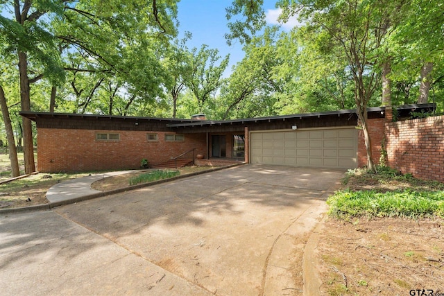 single story home with brick siding, an attached garage, and driveway