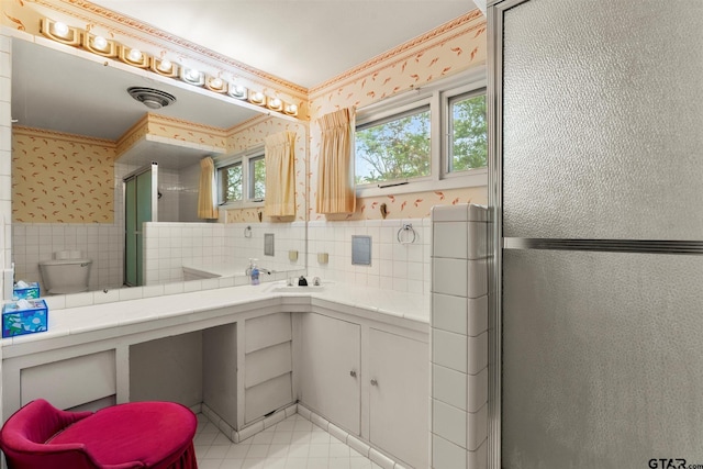 full bath with tile walls, wallpapered walls, vanity, and a shower stall