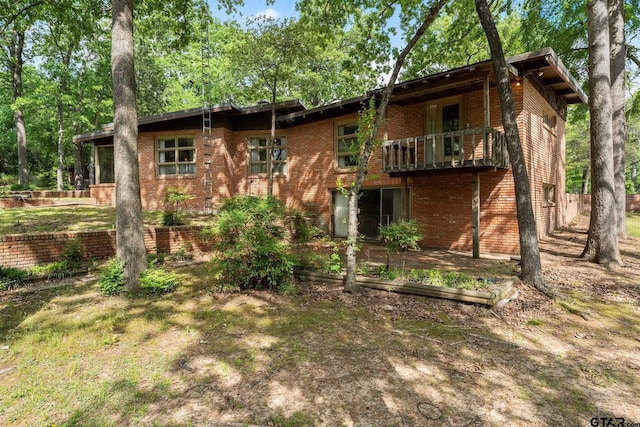 back of property with brick siding and a balcony