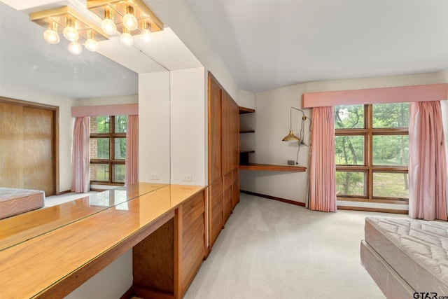 unfurnished bedroom with light carpet, baseboards, a notable chandelier, and multiple windows