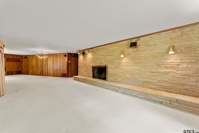 unfurnished living room featuring light carpet, wood walls, visible vents, and a fireplace
