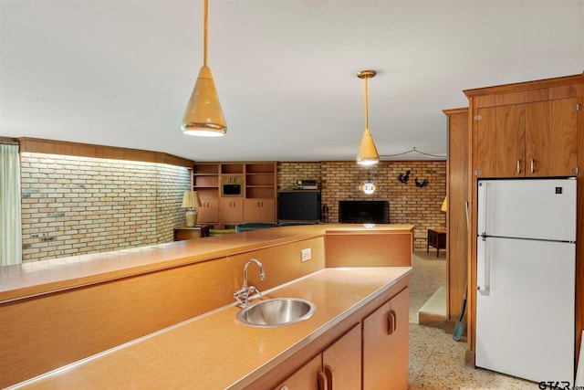 kitchen with a sink, light speckled floor, freestanding refrigerator, light countertops, and hanging light fixtures
