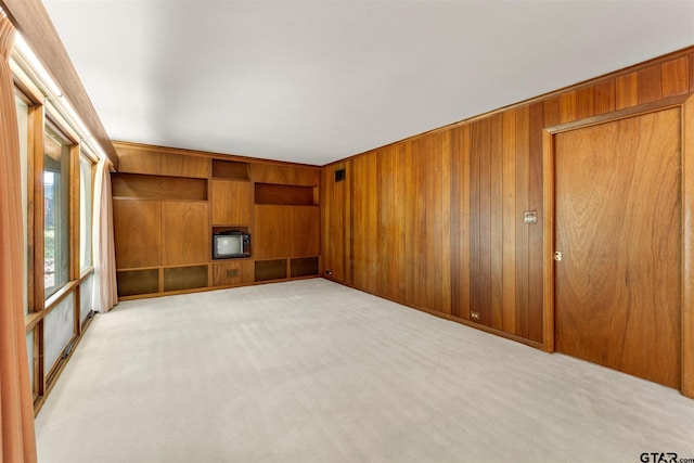spare room featuring wood walls and light colored carpet