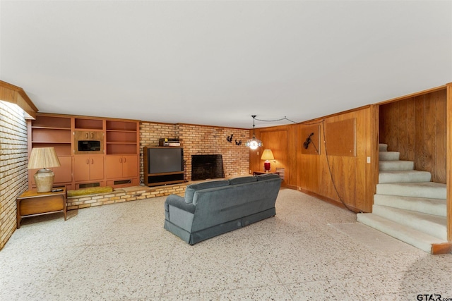 living room with a fireplace, wooden walls, stairway, and speckled floor