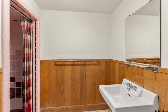 bathroom with wainscoting, a sink, and tiled shower