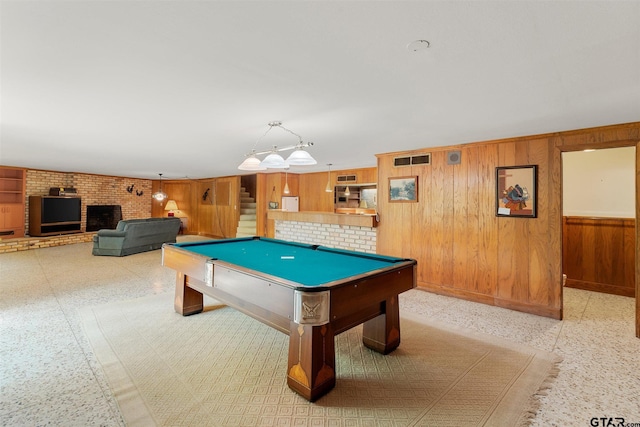 rec room with wooden walls, a brick fireplace, billiards, and visible vents