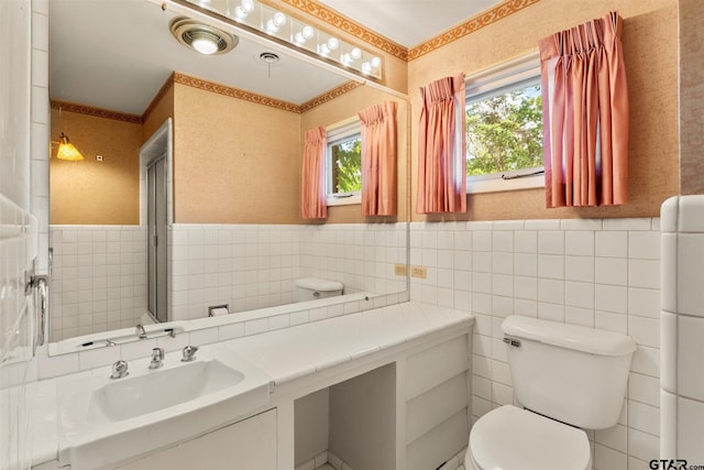 bathroom featuring tile walls, toilet, vanity, and wainscoting