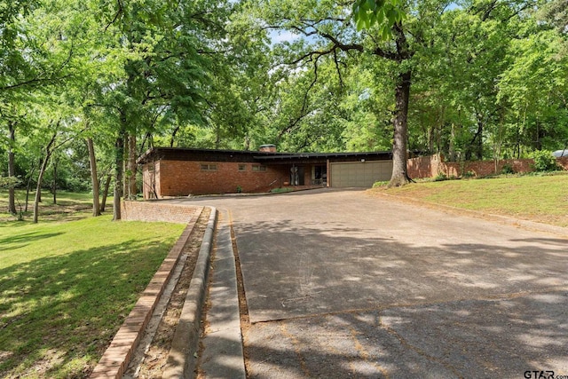 ranch-style house featuring a chimney, aphalt driveway, fence, a front lawn, and brick siding